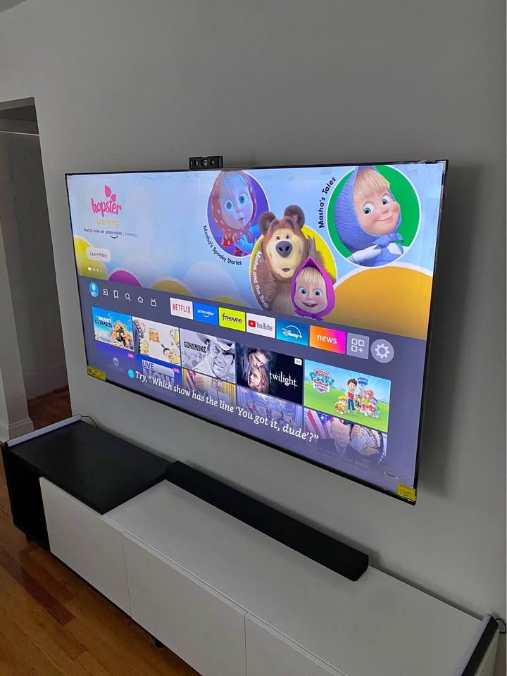 Large TV mounted on drywall above a media console with a soundbar
